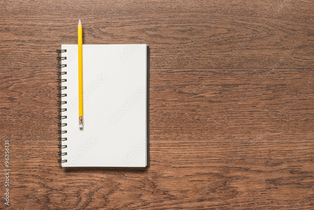 yellow pencil with blank note book on wooden background