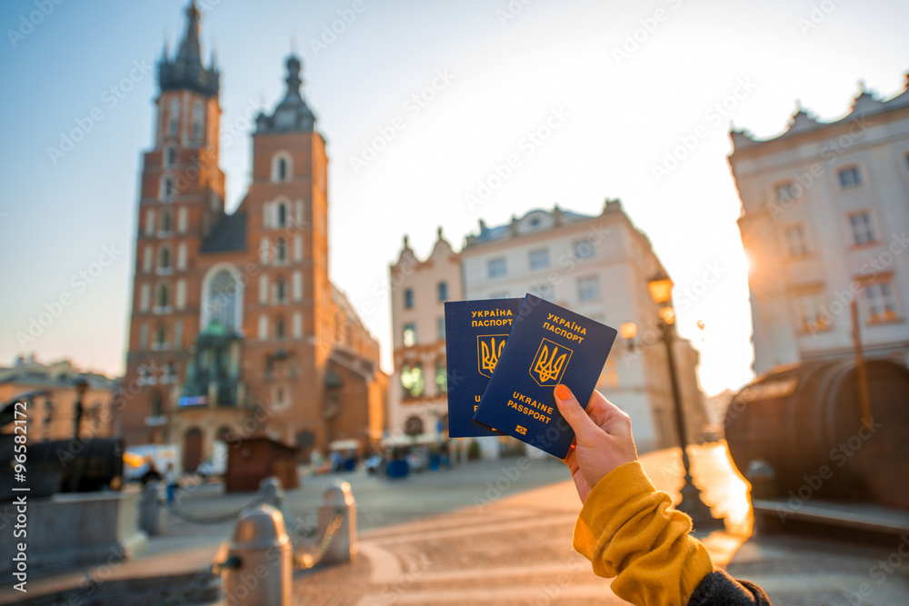 Female hands holding Ukrainian abroad passports on the Krakow city center background