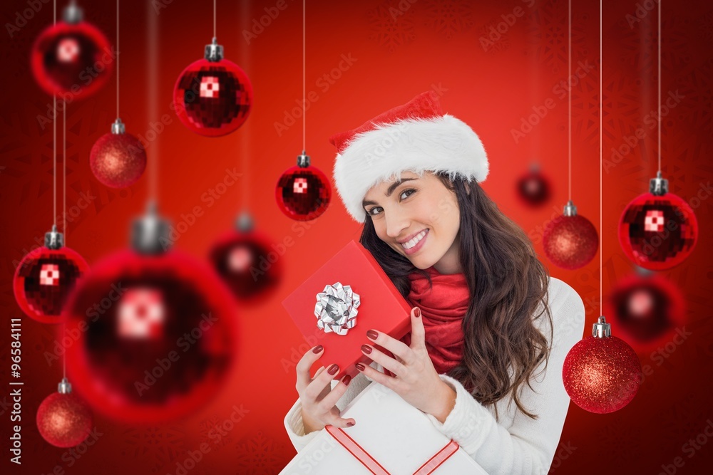 Composite image of smiling brunette holding christmas gifts