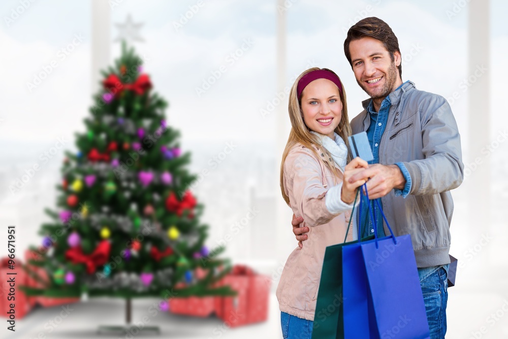 Smiling couple showing credit card and shopping bag