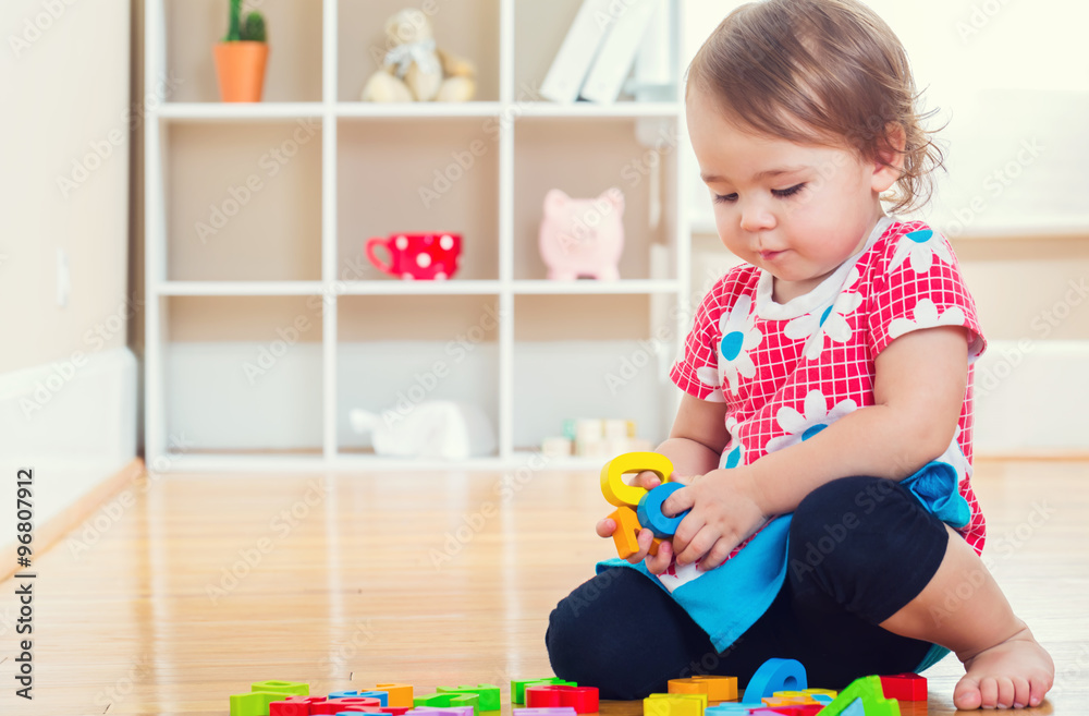 Toddler girl playing with her toys inside