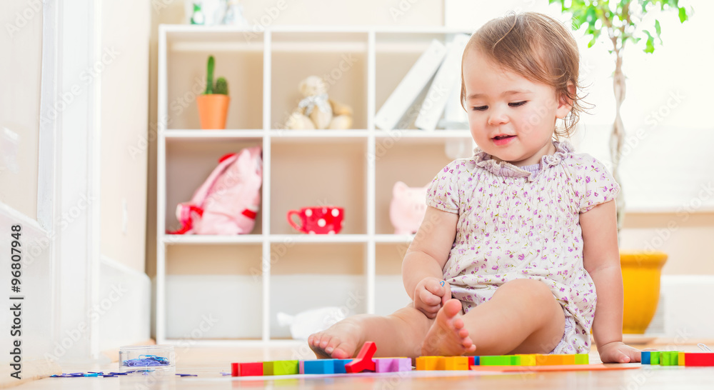 Happy toddler girl playing with her toys