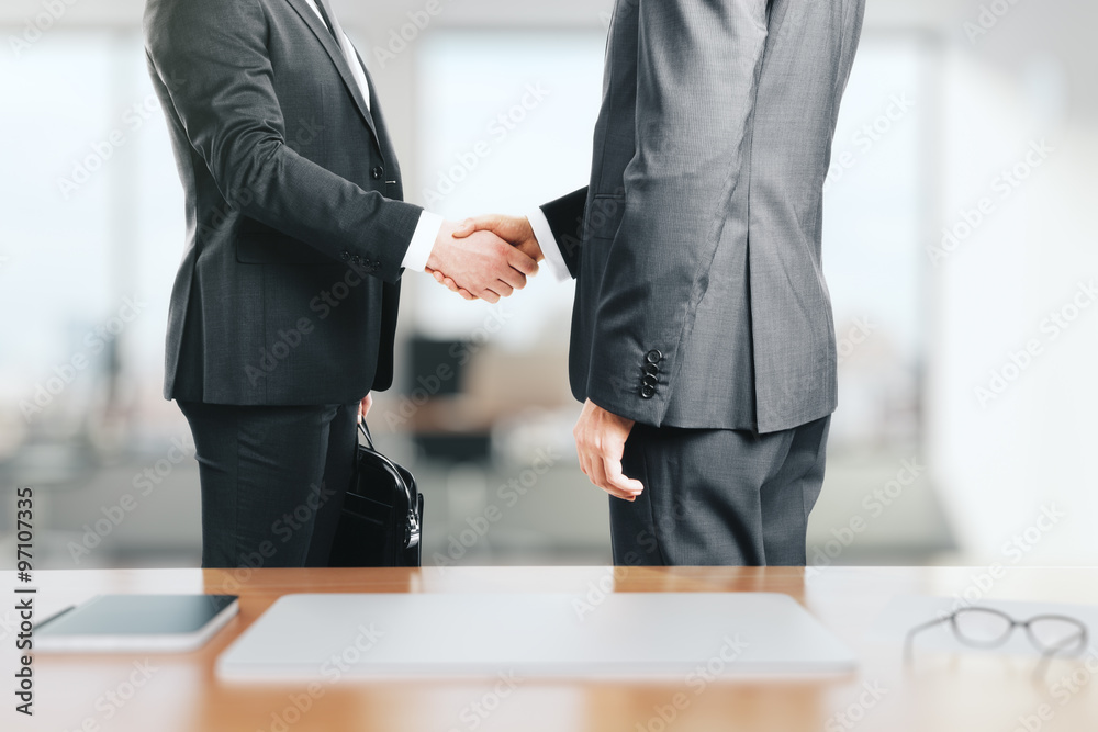 Two businessmen shake hands in the office