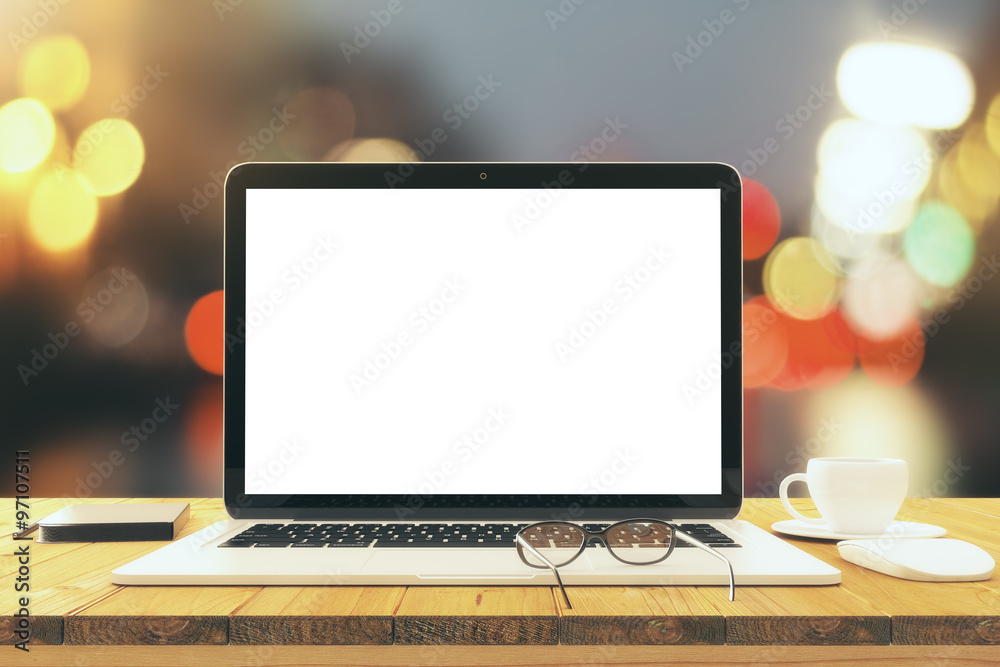 Blank laptop screen on wooden table with eyeglasses and cup of c