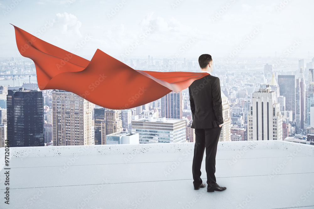 Businessman with red cape staying on the roof of skyscraper