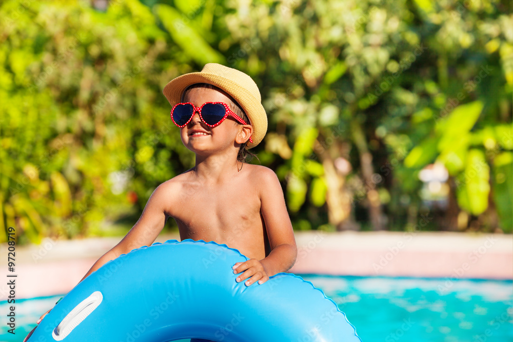 Happy boy with sunglasses holding inflatable ring