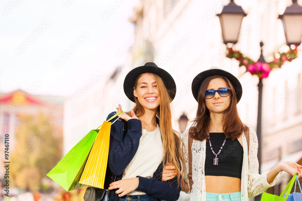 Two stylish young women walking with shopping bags