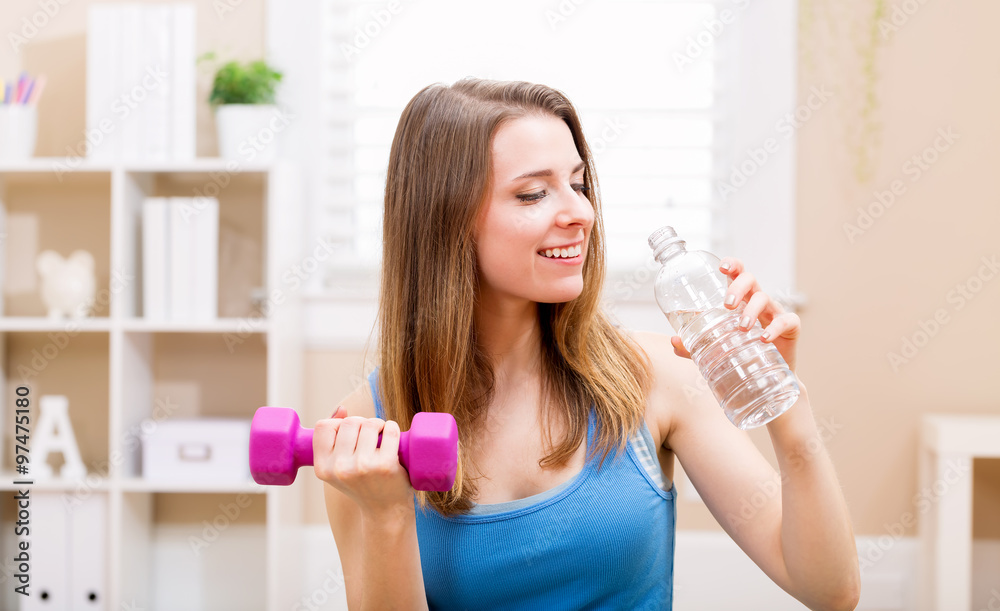 Happy young woman working out with dumbbells