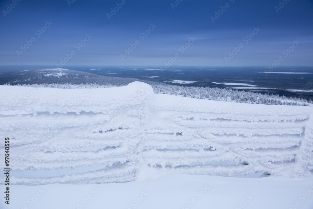 群山背景下被雪覆盖的冰冻围栏