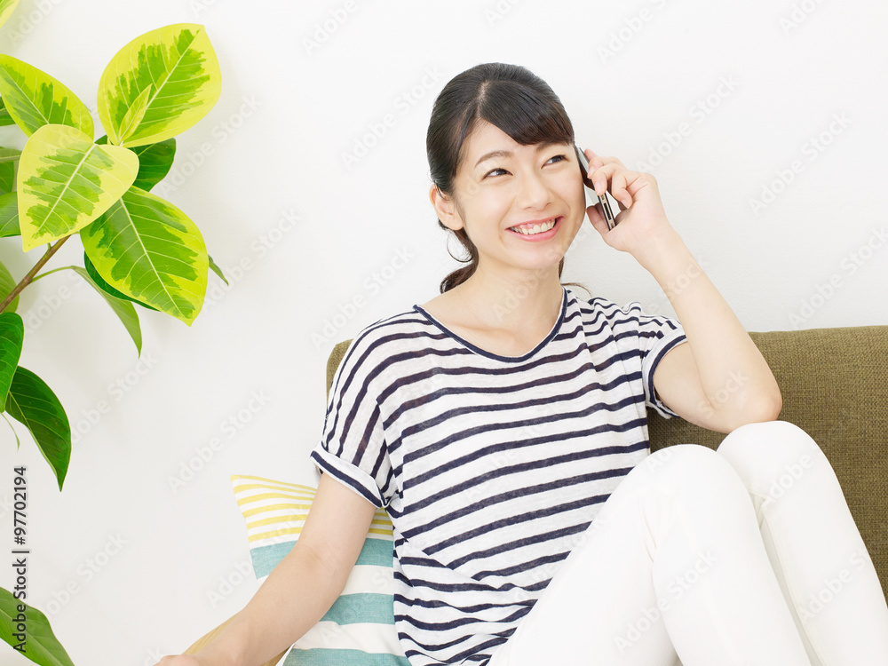 部屋でスマートフォンで話す女性