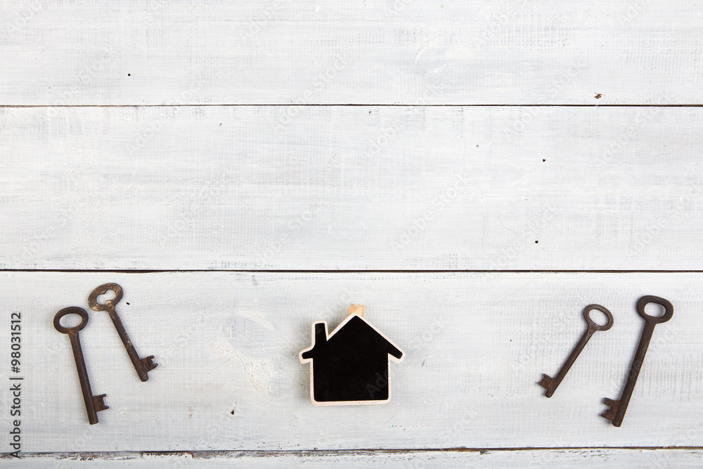 Real estate concept - little house and keys on white wooden desk