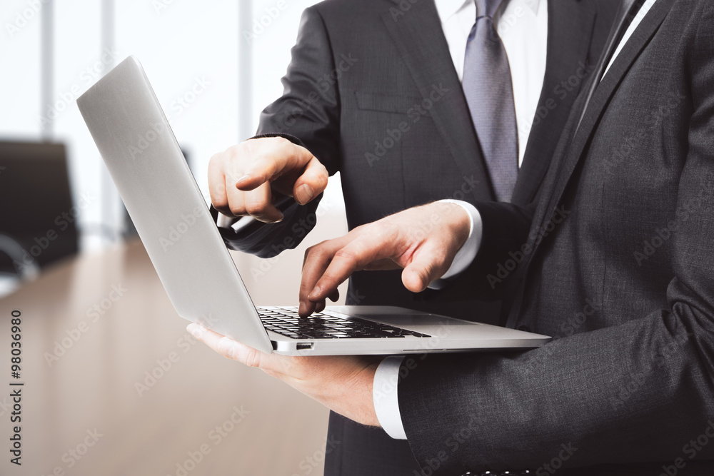 Businessman shows screen of laptop another one in conference roo