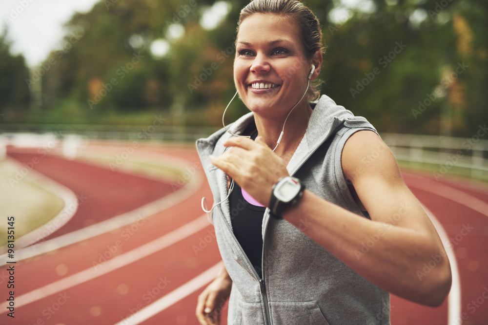 Young smiling woman running on stadium