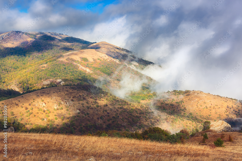 Dramatic mountain autumn landscape at sunset. Low clouds