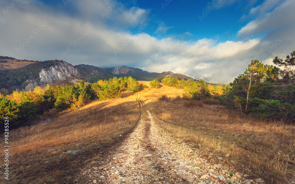 Mountain autumn landscape with road at sunset. Low clouds