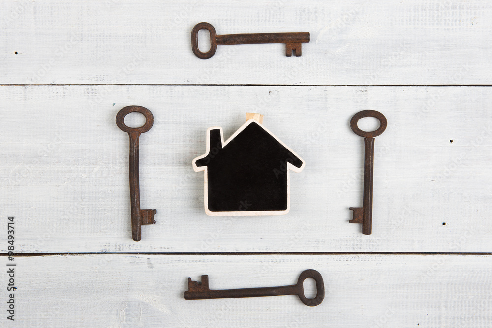 Real estate concept - little house and keys on white wooden desk