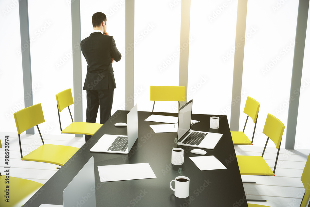 Businessman looking out the window in conference room with furni