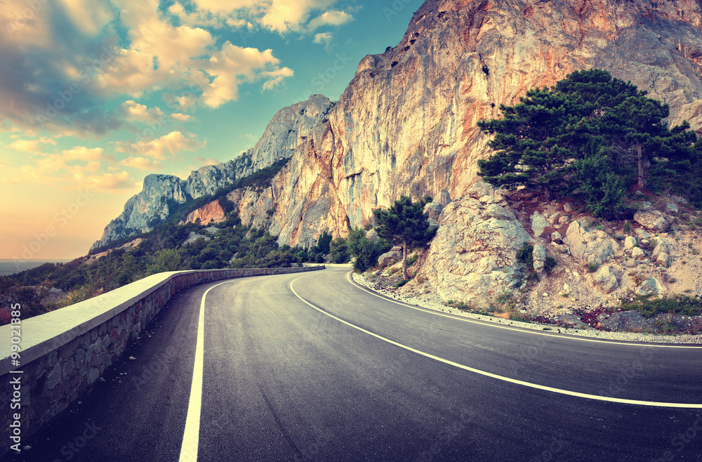 Asphalt road in summer forest at sunset. Crimean mountains