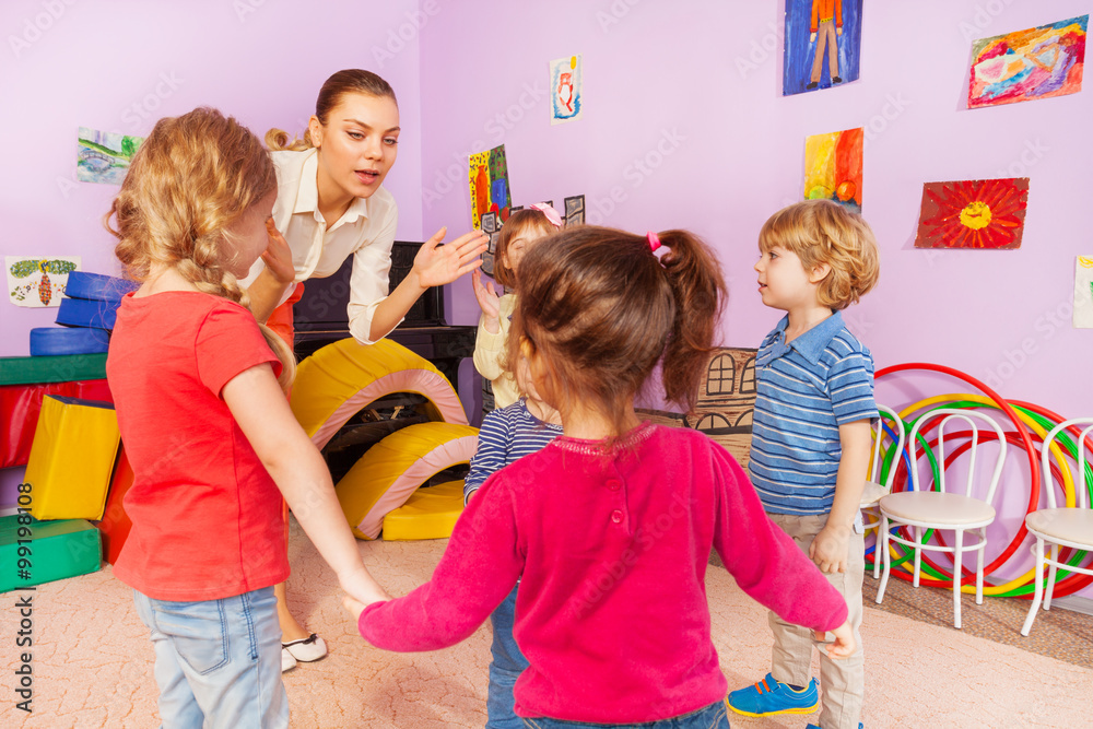 Many kids clap hands with teacher in kindergarten