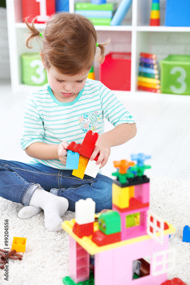 child girl playing with toys and builds constructor