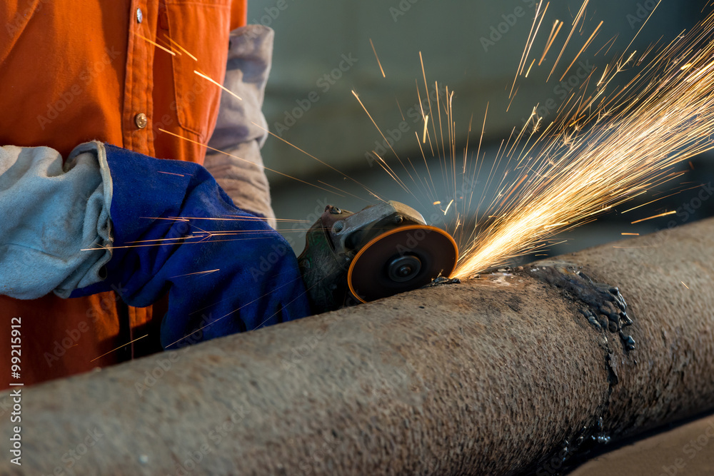 Worker cutting metal with grinder. Sparks while grinding iron