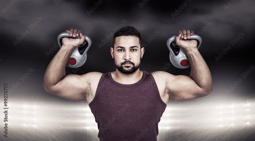 Composite image of muscular serious man lifting kettlebells