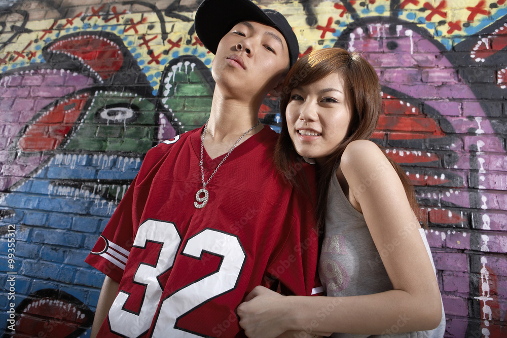 Teenage Boy And Girl In Front Of A Wall Of Graffiti