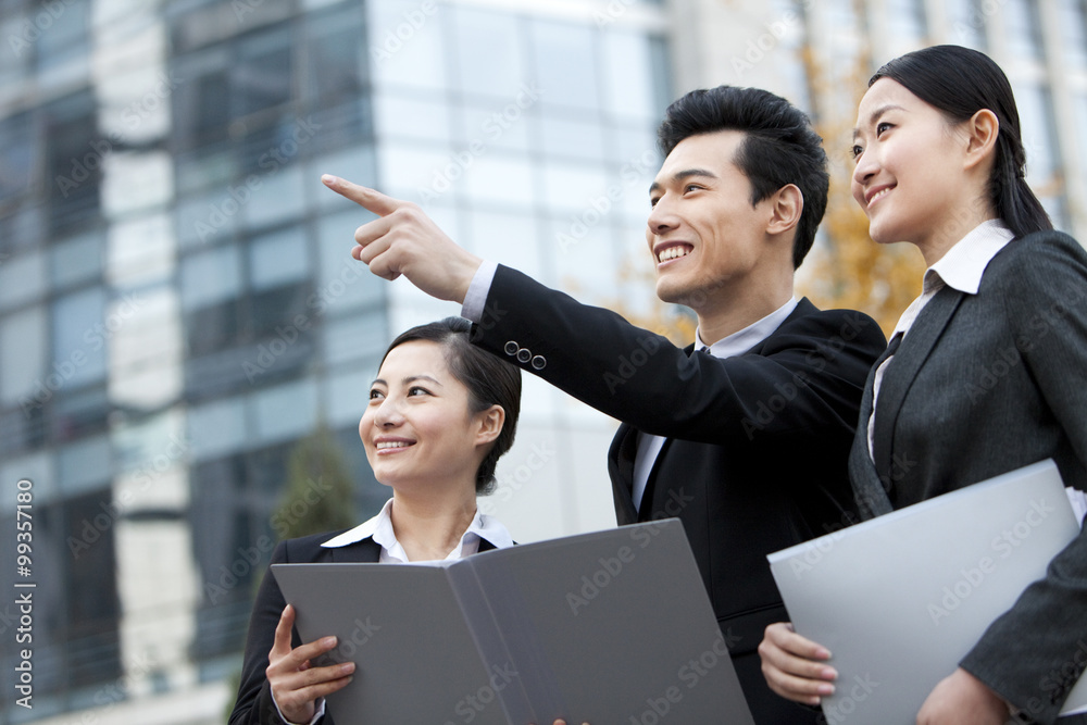 A team of businesspeople outside office buildings pointing and planning