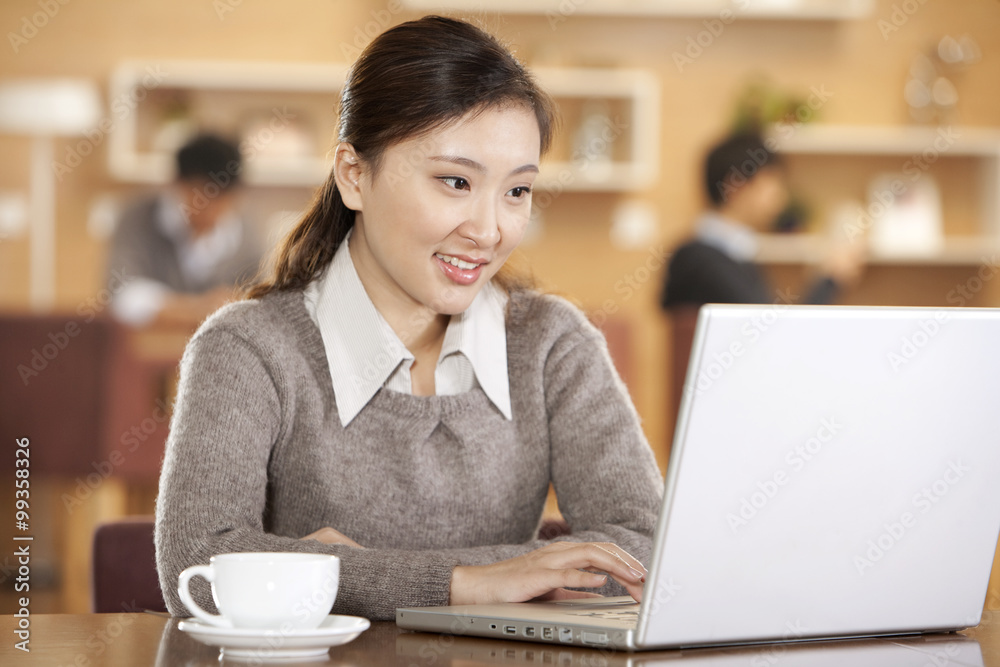 young woman using laptop in coffee shop