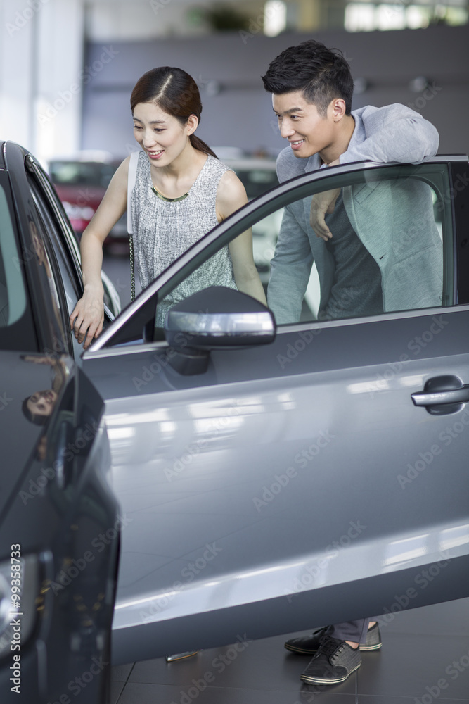 年轻夫妇在展厅里看新车