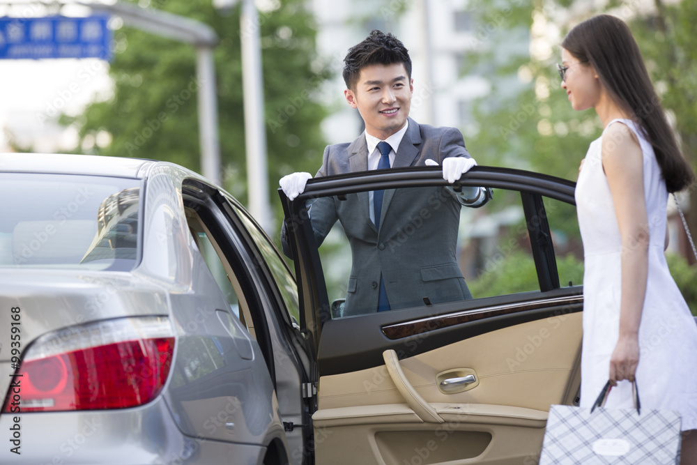 Chauffeur opening car door for a young woman