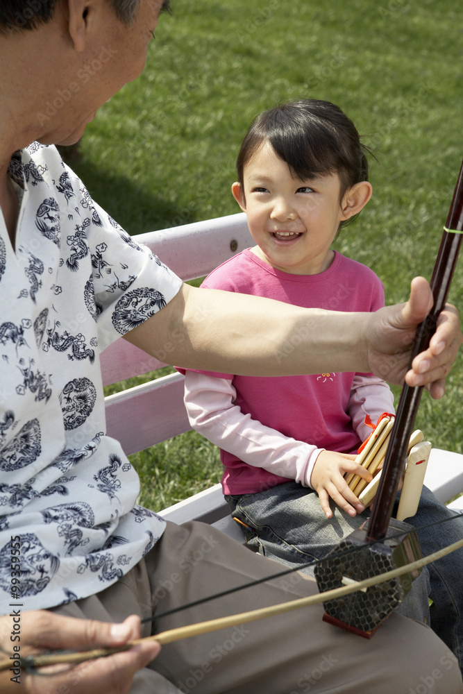 Grandfather Playing Granddaughter Instrument