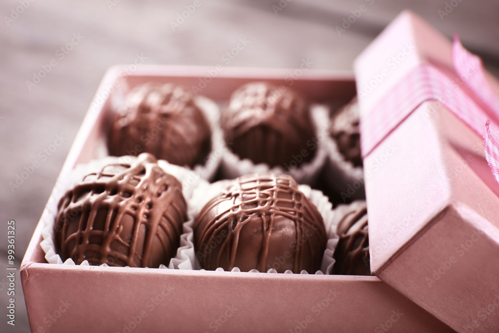 Tasty chocolate candies in pink gift box on wooden background, close up