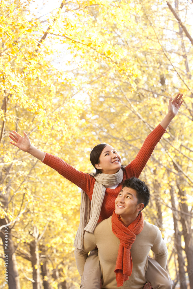 Young couple with arms outstretched, Autumn leaves in the background