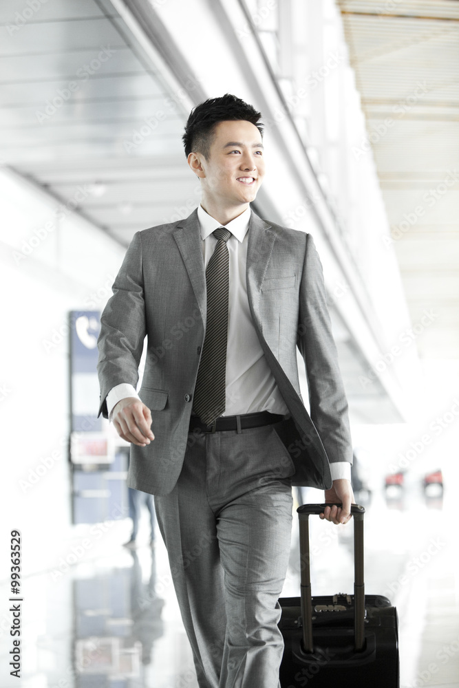 Businessman pulling wheeled luggage in airport lobby