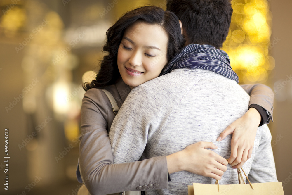 Sweet young couple embracing with shopping bag in hands