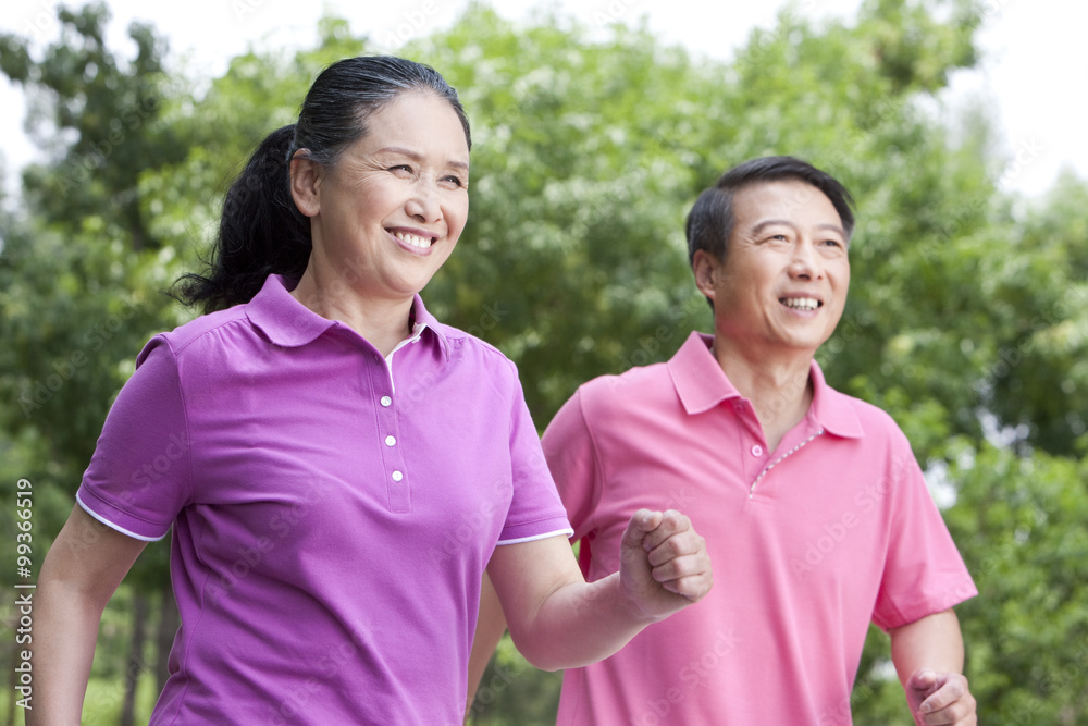 Senior couple running in park