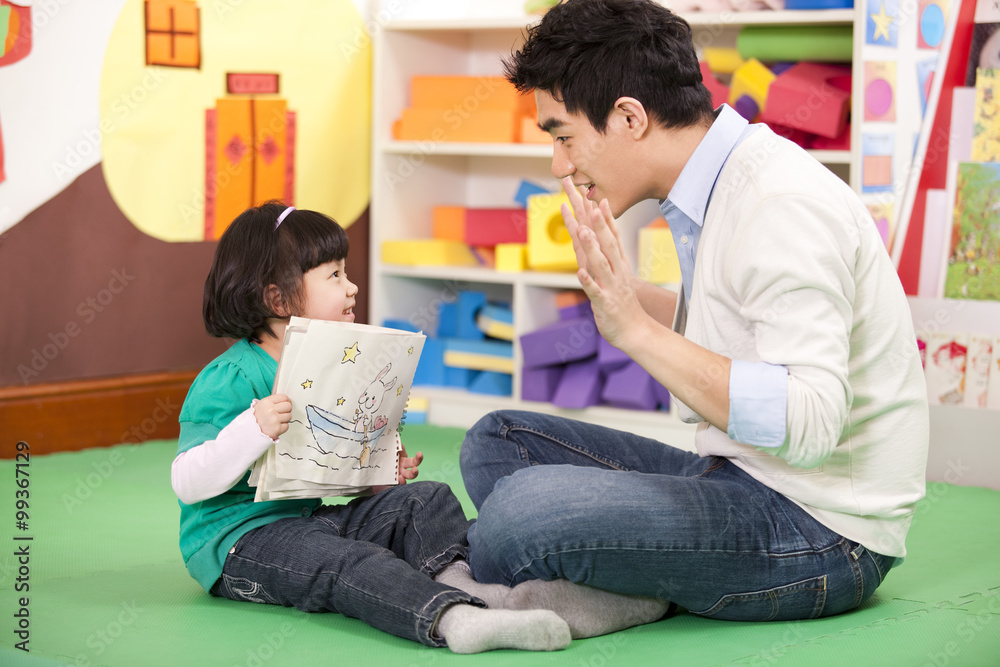 Male teacher sitting on floor with cute girl