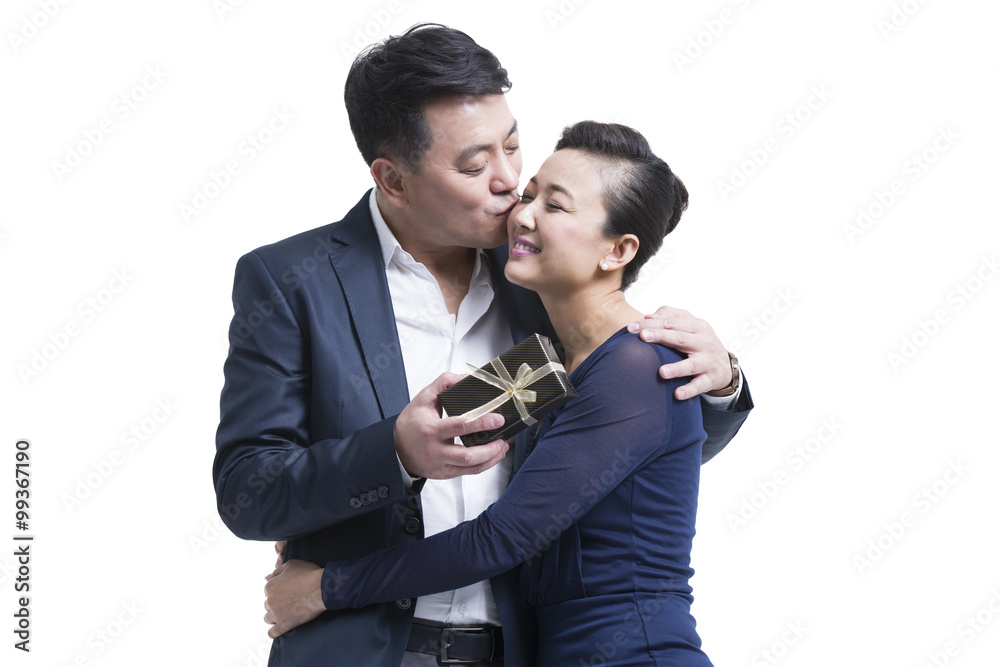 Husband kissing wife with gift in hand