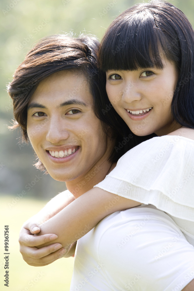 Young man carrying young woman on back