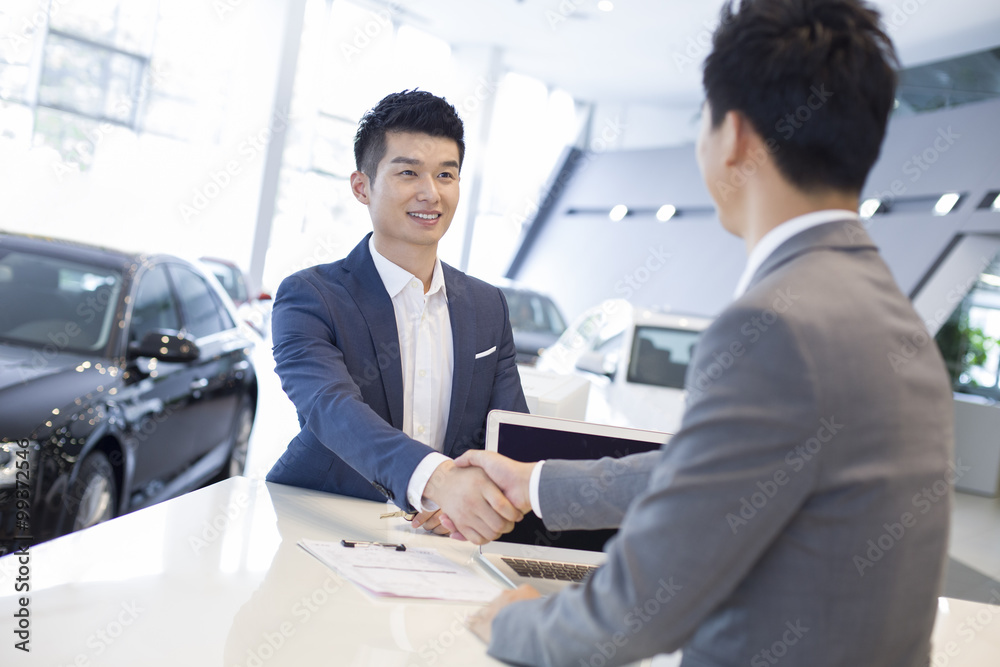 Young man buying car in showroom