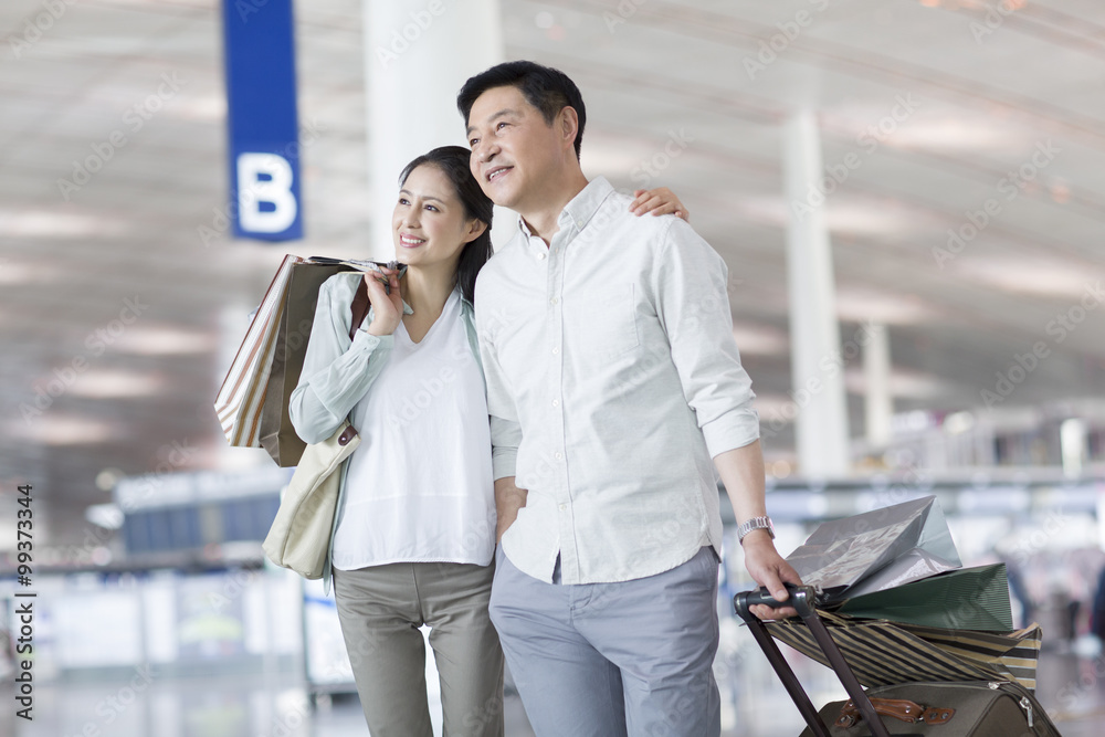 Mature couple waiting at airport with shopping bags