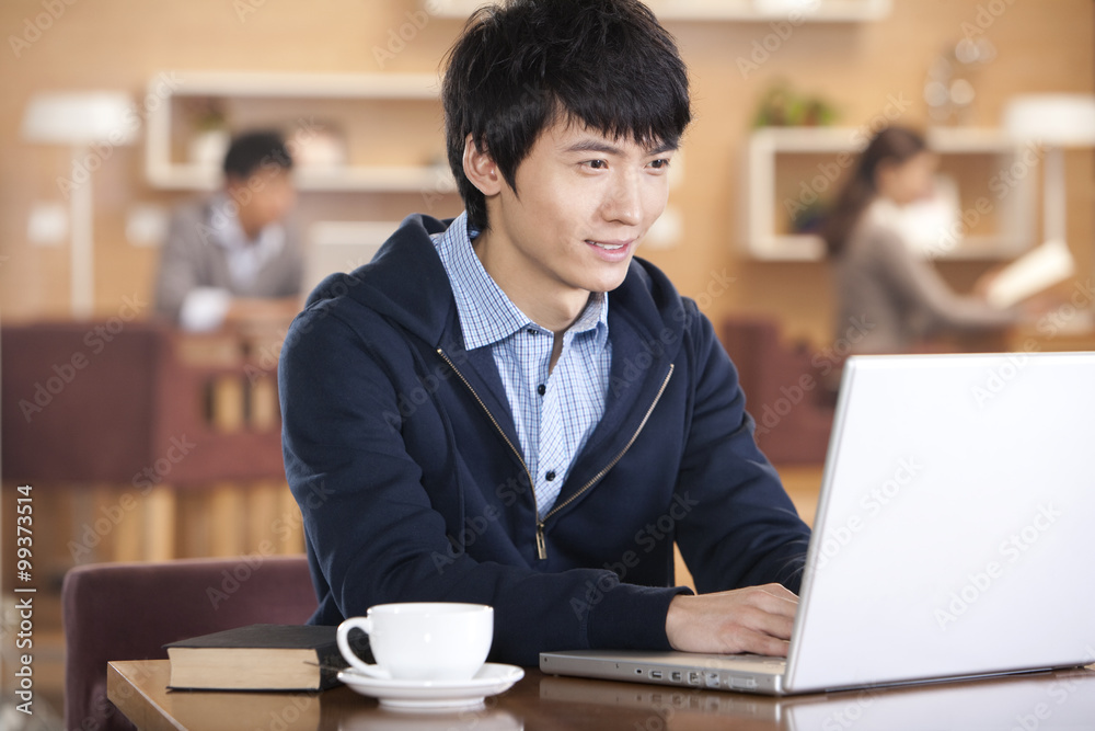 Young man using laptop at coffee shop