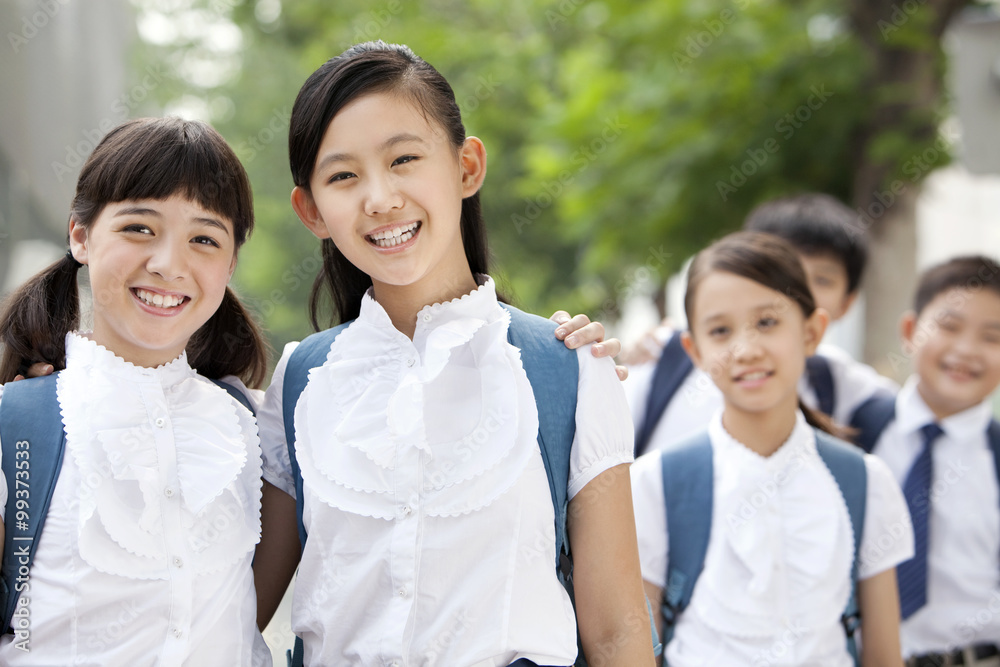 快乐的穿着制服的女学生和朋友在户外