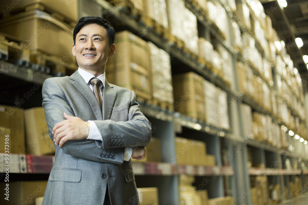 Confident businessman arms crossed in warehouse