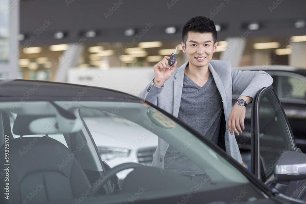 Young man buying car in showroom