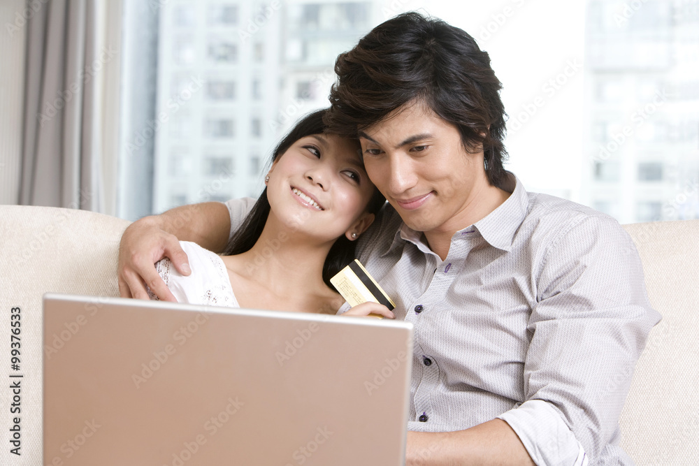 Asian couple cuddling on a sofa