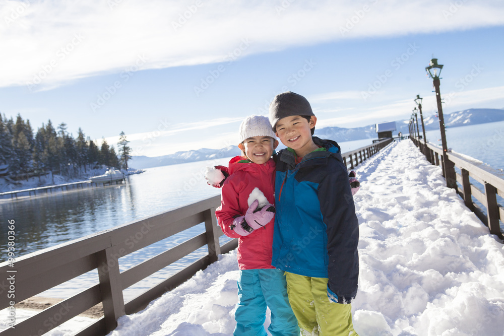 Boy and girl arm around with snowball in hand