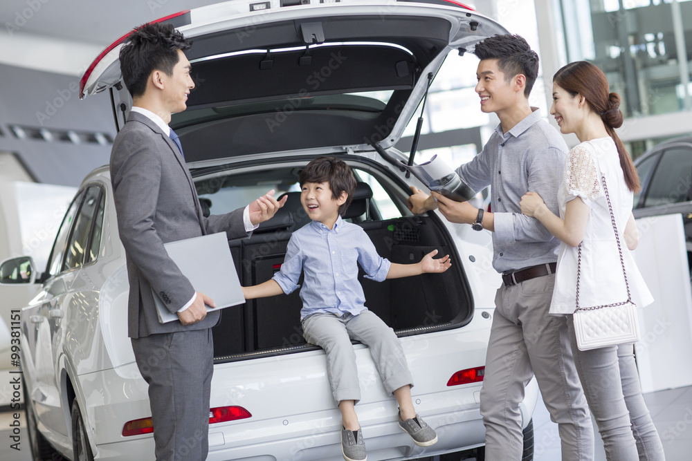 Young family choosing car in showroom