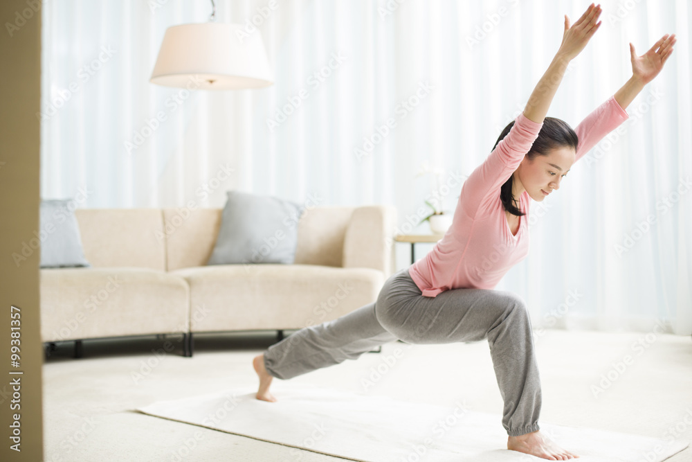 Young woman practicing yoga in living room